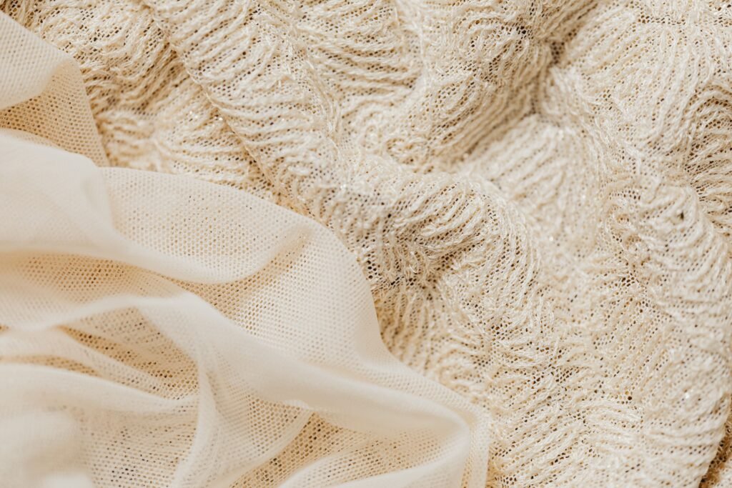 Dresstime Close-up view of intricate beige lace fabric and sheer material, ideal for fashion and textile projects.